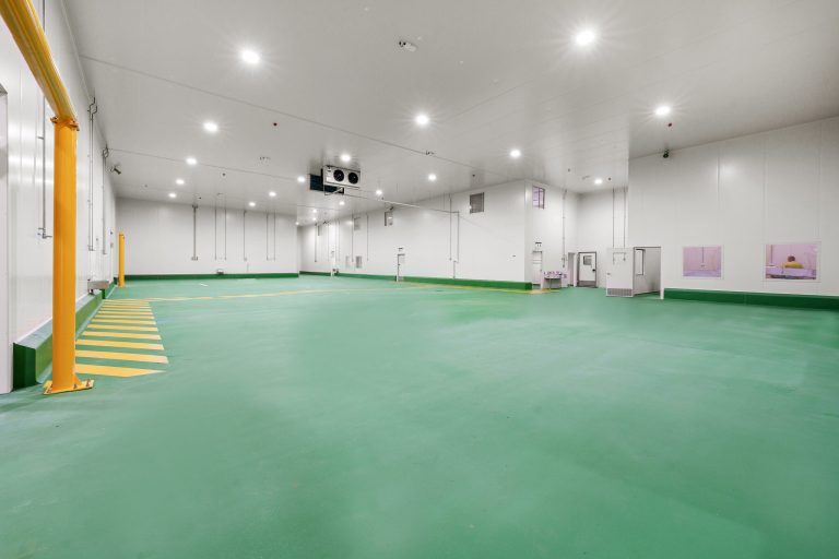 Green epoxy floor in a food processing facility with safety bollards