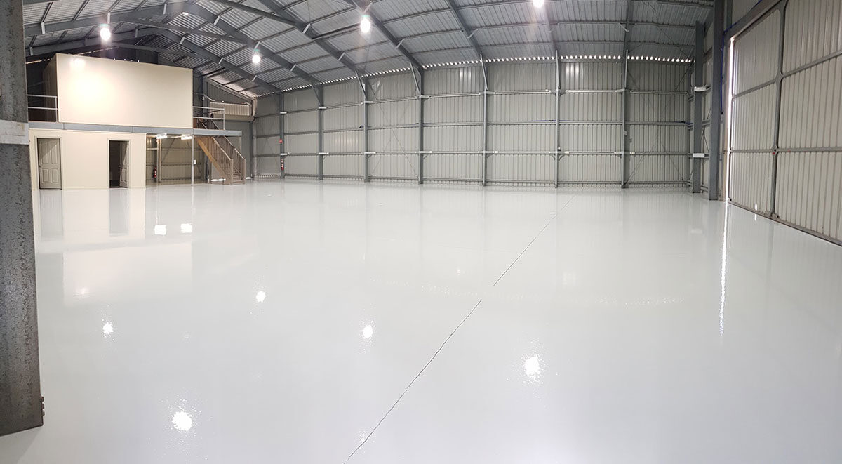 Glossy light grey epoxy floor in a clean warehouse shed